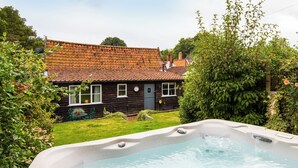 A house with a tiled roof, a hot tub, and a well-maintained garden. - 2 bedroom accommodation in Coltishall (Coltishall)