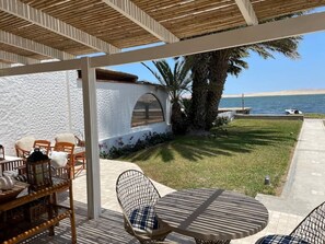 Un área de estar al aire libre con techo, muebles de mimbre y vista al mar.