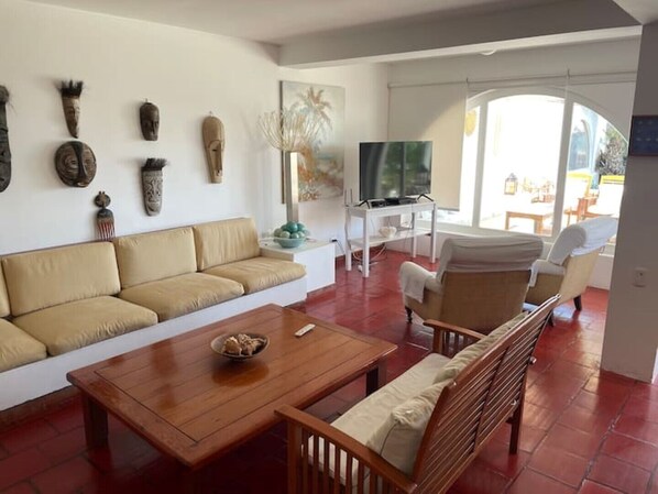 Una sala de estar con sofá, mesa de centro de madera y televisor.