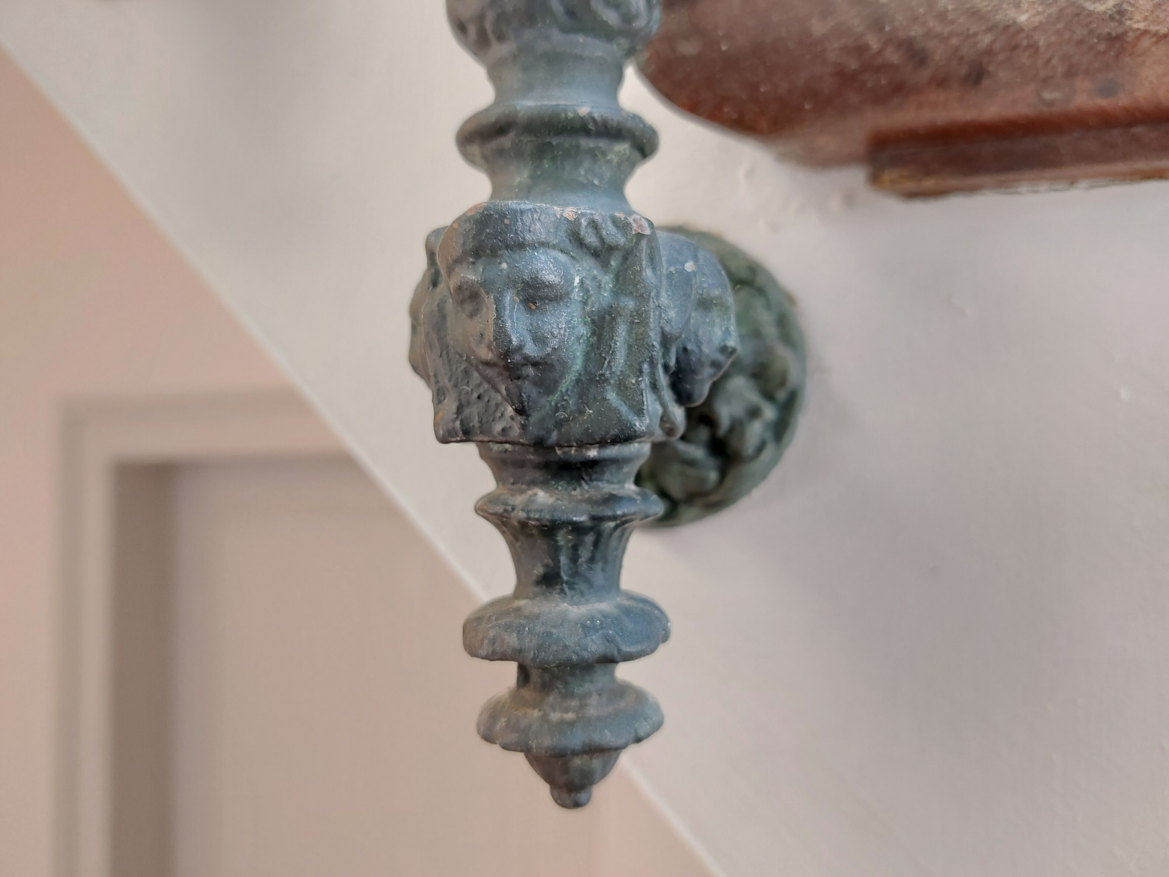 A close-up of a decorative metal bracket with a lion's head design, attached to a wall.