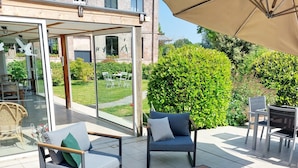 Un patio al aire libre con mobiliario moderno, que incluye un sofá, sillas y una mesa.