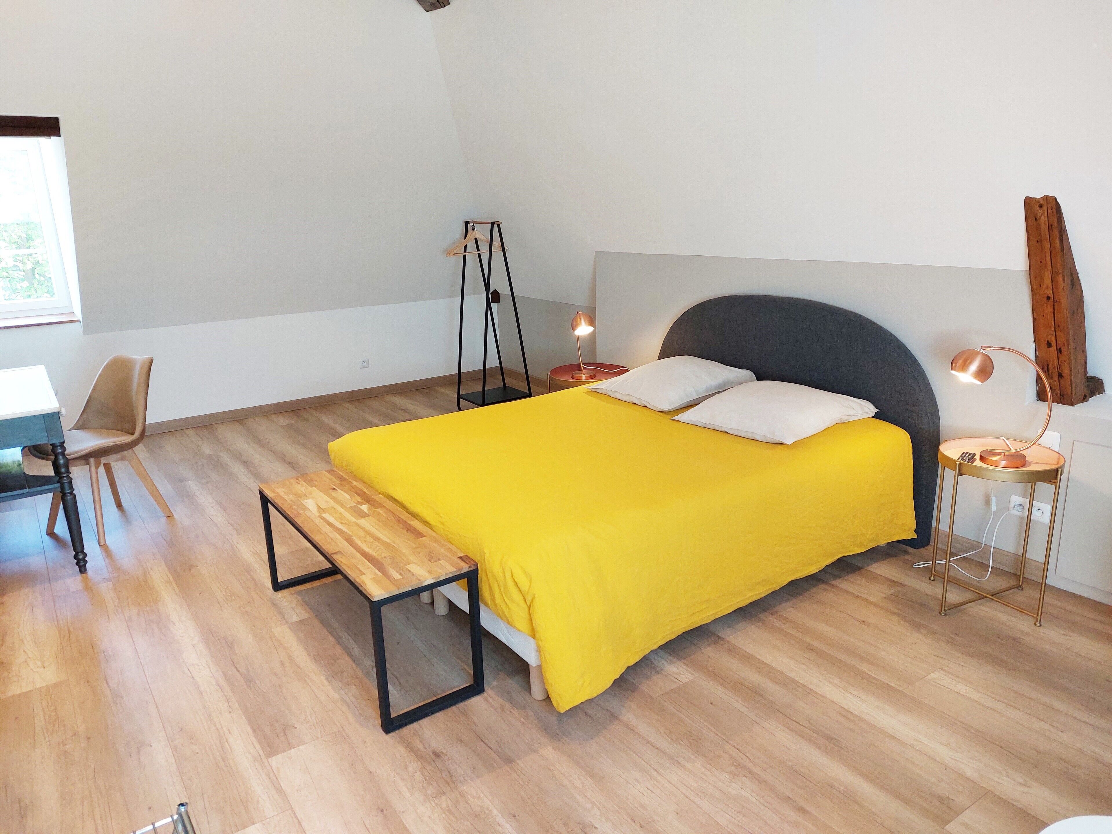 Een slaapkamer met een bed, nachtkastjes, een stoel en een bankje.