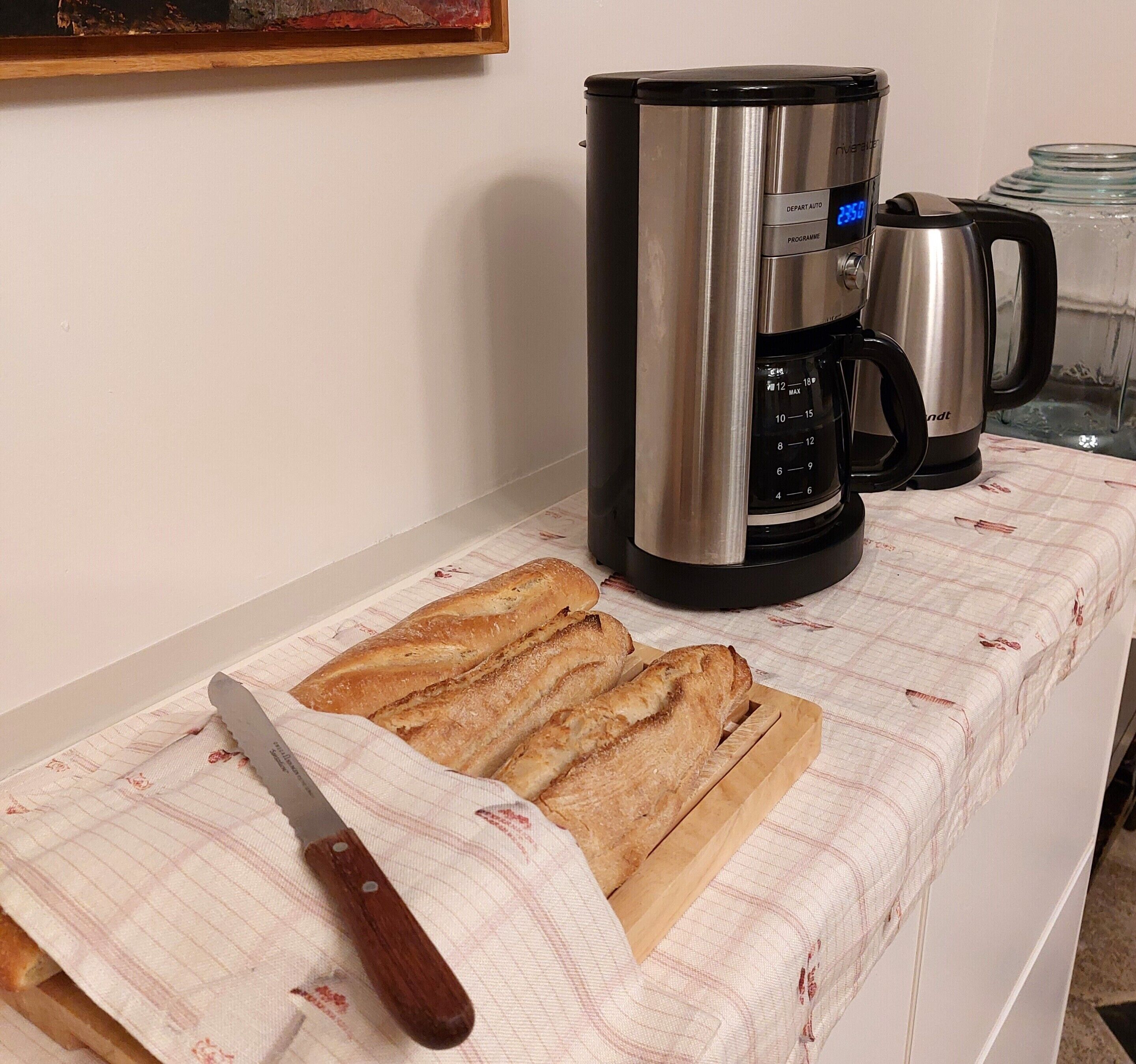 A kitchen counter with a cutting board, a knife, and two coffee makers.