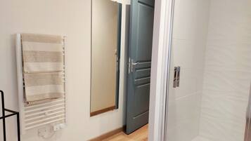 Un baño con toallero, puerta y zona de ducha.