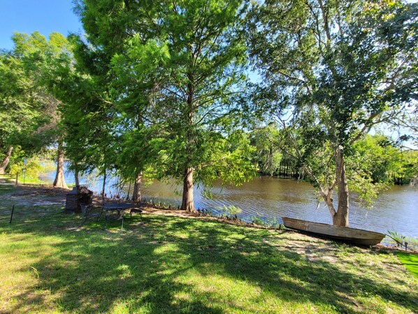 A lakeside campsite with trees, a picnic table, and a boat.