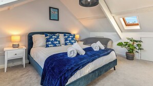 A bedroom with a bed, bedside lamps, a framed picture, a skylight, and a potted plant. - Y Tŷ Glas is a charming terraced cottage in New Quay. (New Quay)
