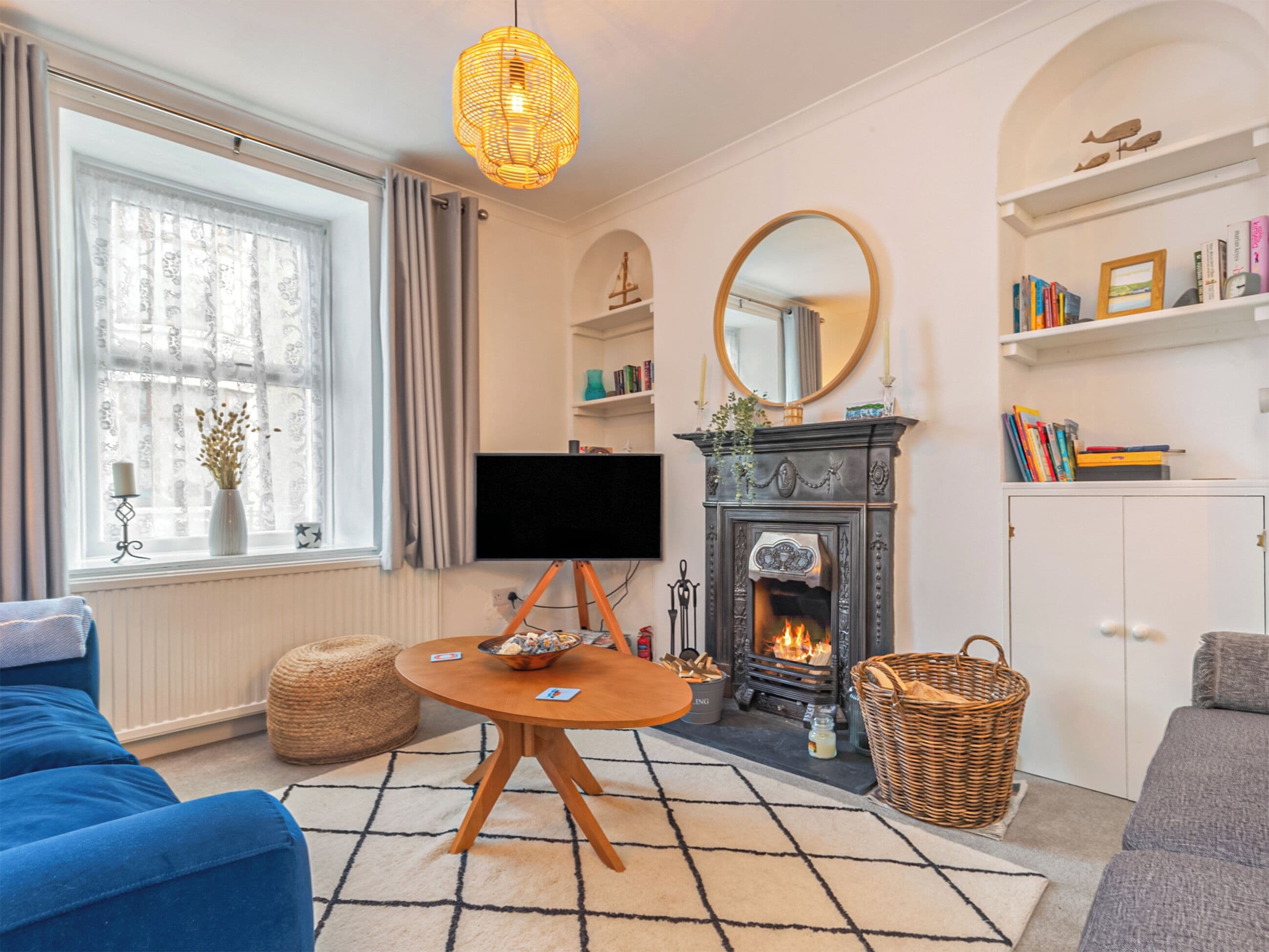 Una sala de estar acogedora con chimenea, televisor, estantería y un espacio de descanso cómodo.