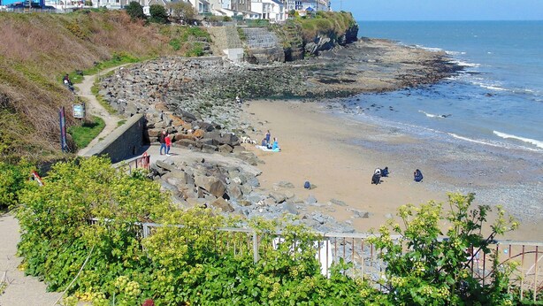 A coastal town with terraced houses, a rocky beach, and a clear view of the sea. - Y Tŷ Glas is a charming terraced cottage in New Quay. (New Quay)