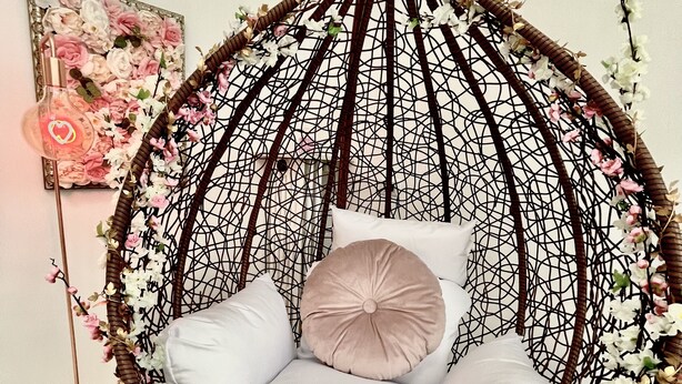 Un fauteuil suspendu avec des coussins blancs et un filet décoratif.