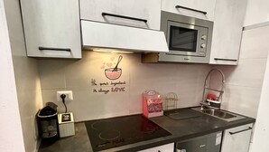 Une cuisine compacte équipée d’un four à micro-ondes, d’une machine à café et ornée d’un message sur le mur.