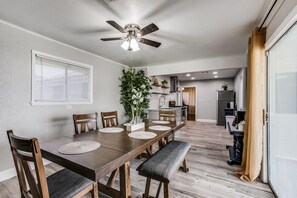 A dining area with a wooden table, chairs, and a ceiling fan.