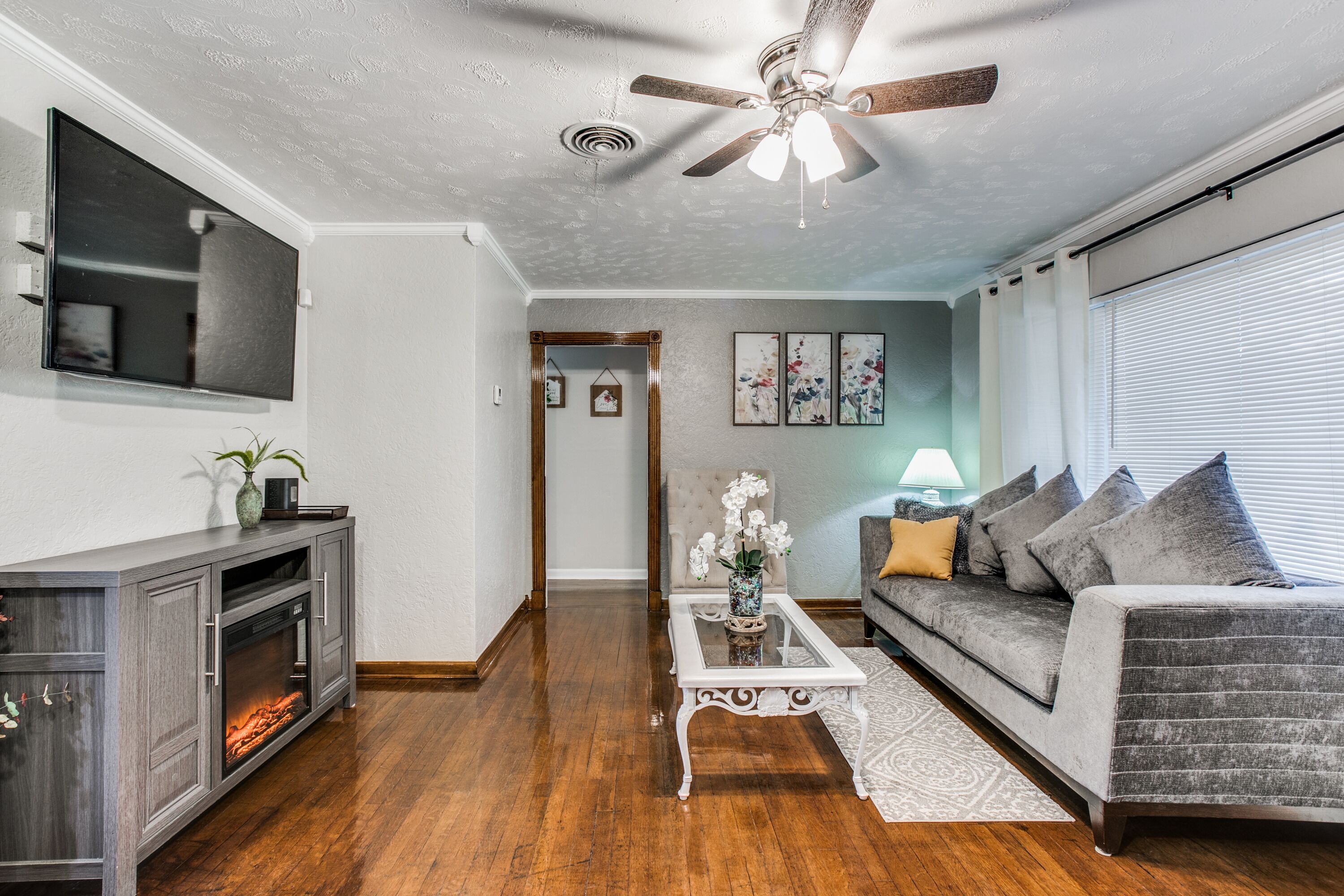 A living room with a fireplace, a sofa, a coffee table, and a ceiling fan.