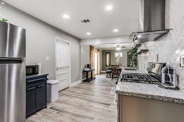 A modern kitchen with stainless steel appliances, a granite countertop, and a dining area with a chandelier.