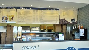 Een menubord met Welsh Ice Cream en Hooked @ 31 branding, een koffiemachine en een toonbank met verschillende etenswaren.