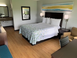 Een hotelkamer met een bed, nachtkastjes, een bureau, een stoel, een spiegel en een schilderij aan de muur.
