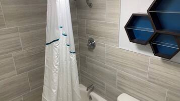 A bathroom with a shower curtain, a bathtub, a toilet, and a hexagonal shelf unit.