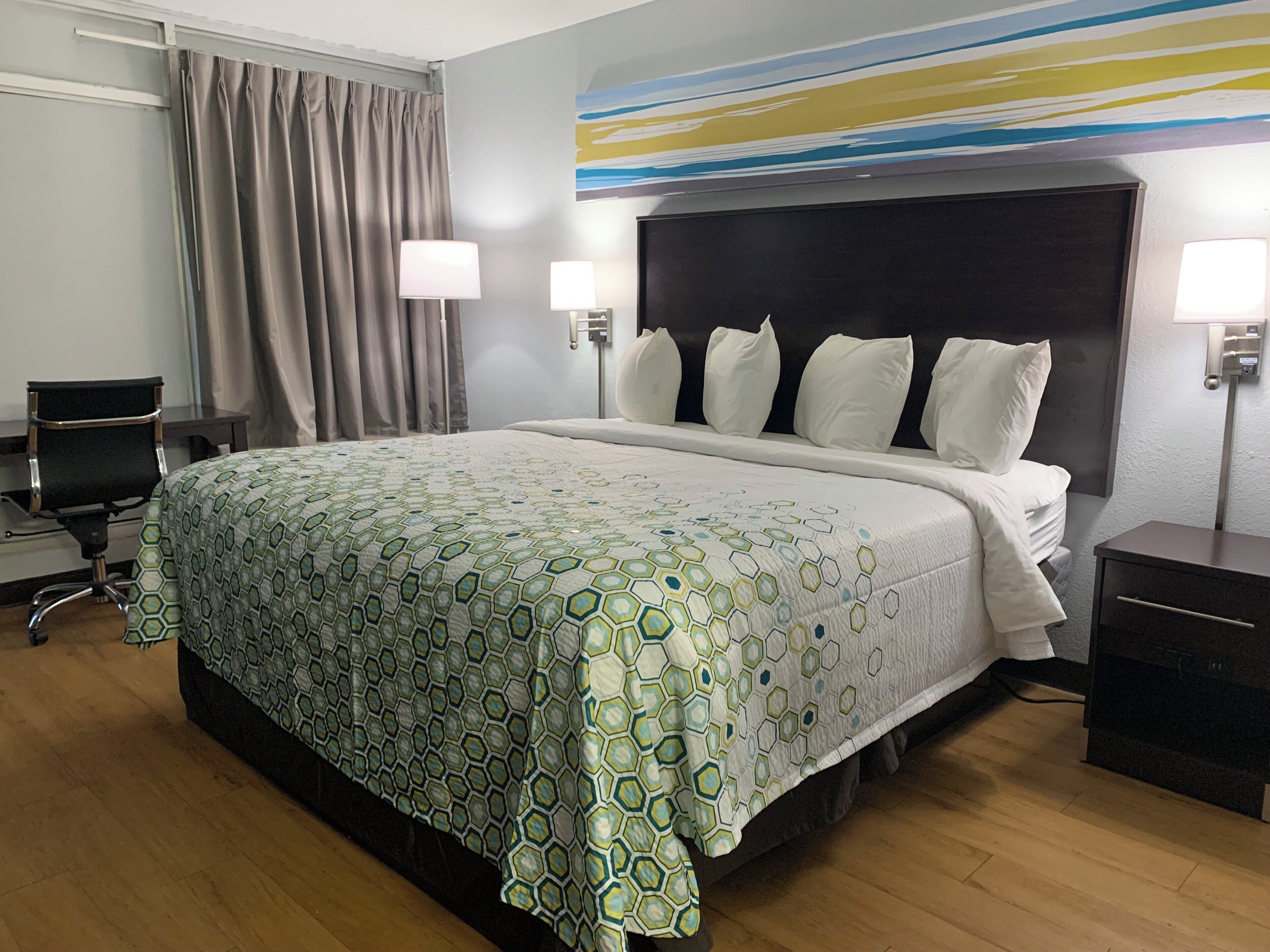 Een hotelkamer met een groot bed, twee bedlampen, een bureau en een stoel.