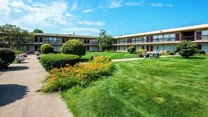Un motel à deux étages doté d’une pelouse bien entretenue, d’un chemin et d’un petit jardin agrémenté de fleurs.