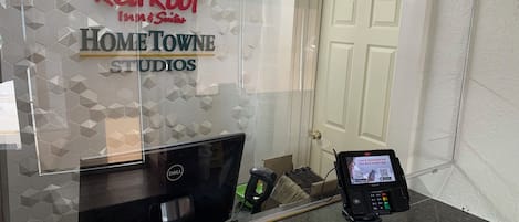 Una recepción con una computadora Dell, un terminal de pago y el letrero de Red Roof Inn & Suites.