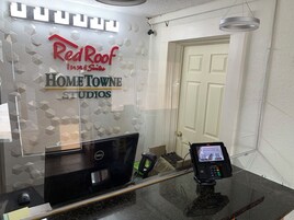 A reception desk with a Dell computer, a payment terminal, and a Red Roof Inn & Suites sign.
