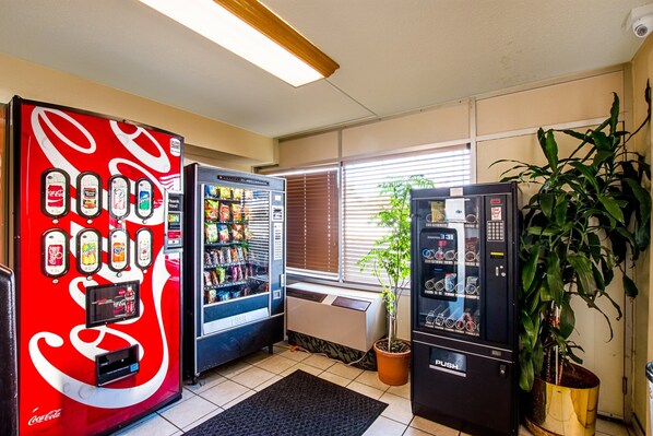 A vending area with Coca-Cola and Pepsi machines, a beverage dispenser, and a potted plant. - HomeTowne Studios by Red Roof Battle Creek (Battle Creek)