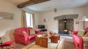 Una sala de estar con un sofá rojo, una mesa de centro de madera, una chimenea de piedra y un televisor.