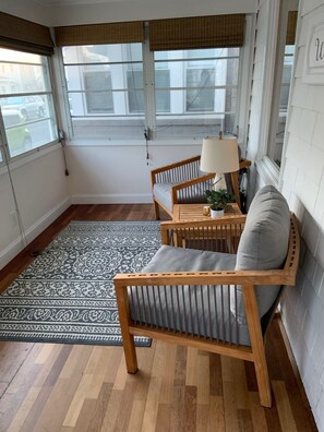 Una habitación con alfombra estampada, muebles de madera y una ventana con persianas.