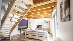 A loft-style room with a wooden staircase, a bed, a desk, and a television. - Apartment Comfortable in the centre of Pau: parking, AC... (Pau)