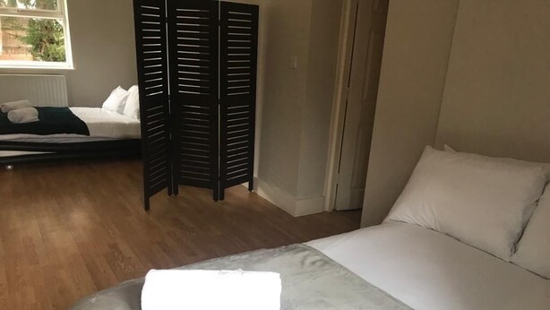 A bedroom with a bed, a window, and a wooden floor.