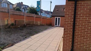 A paved pathway leading to a brick building with a door.