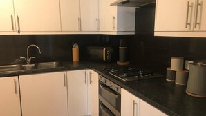 A modern kitchen with white cabinets, a black countertop, stainless steel appliances, and a wooden utensil holder.