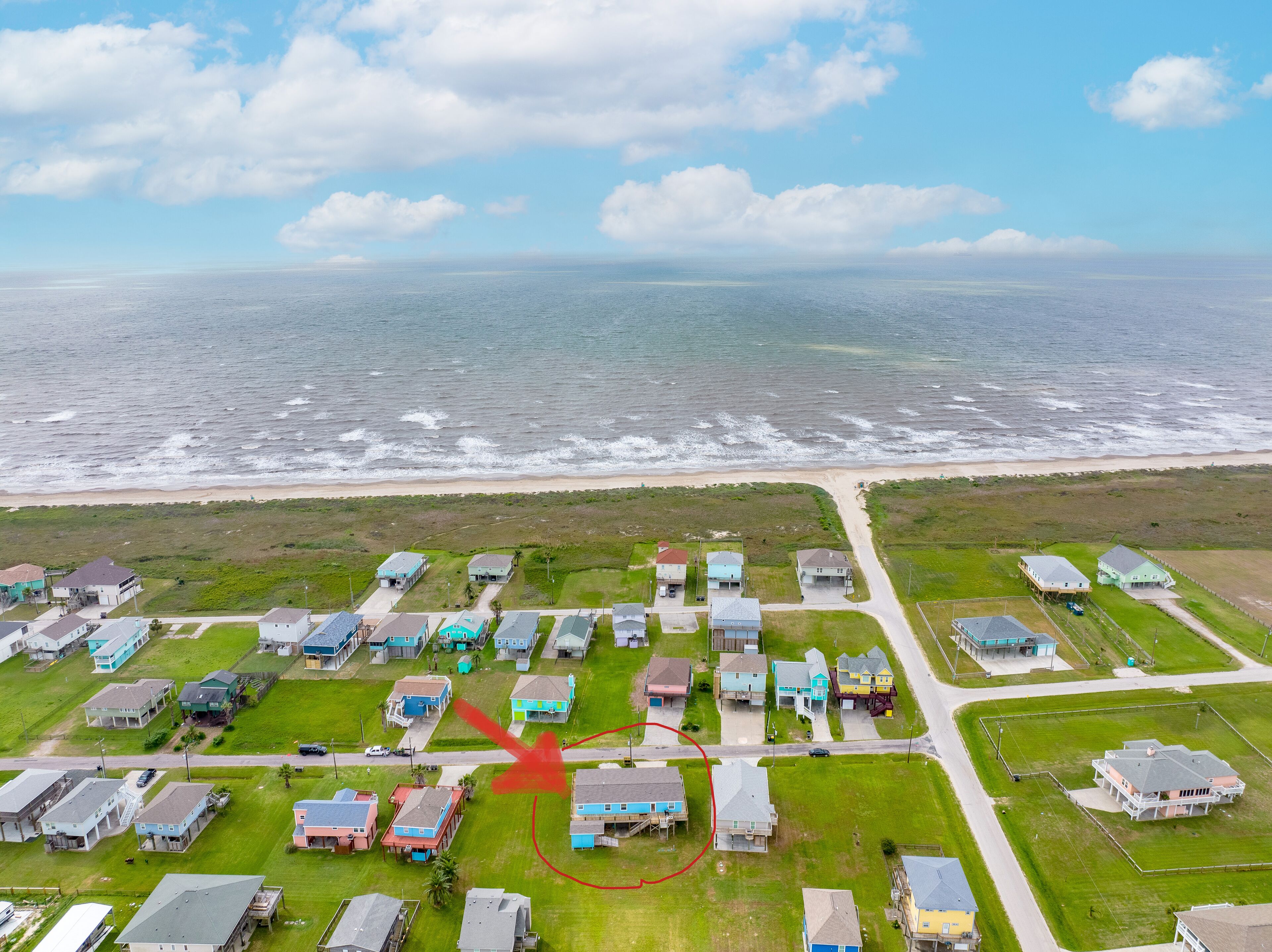 An aerial view of a coastal residential area with houses and a beach.