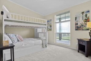 A child's bedroom with bunk beds, a window with blinds, and a painting on the wall.