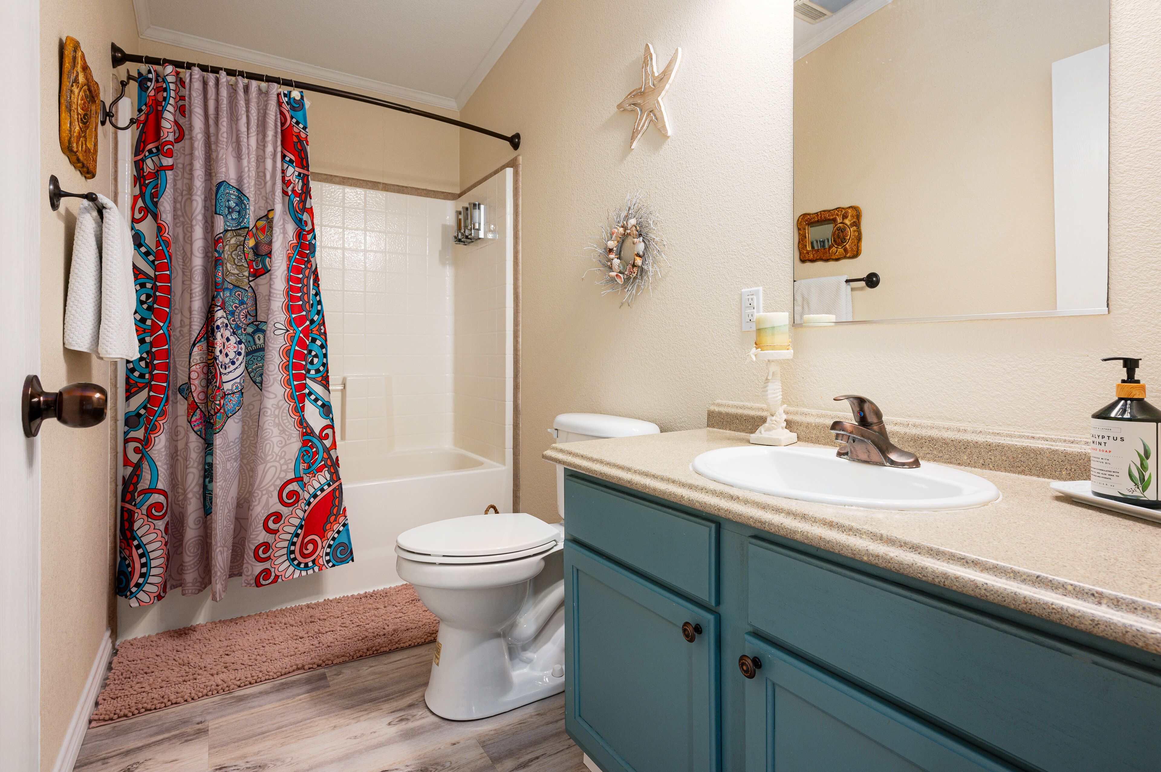 A bathroom with a shower curtain, toilet, sink, and vanity.
