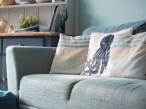 A grey sofa with a patterned cushion and a blue pillow with an octopus design.