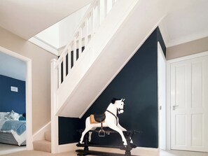 A staircase with a white railing and a black and white horse sculpture at the bottom.