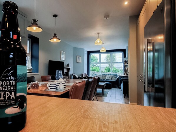 A modern kitchen with a dining area, large windows, and a bottle of beer on the table.
