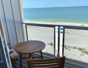 A wooden deck with a round table and chairs, overlooking a beach with a clear view of the ocean and a distant shoreline. - Beautiful Oceanfront Townhome in Mexico Beach, Fl (Mexico Beach)