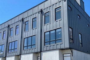 Un bâtiment moderne à la façade grise et doté de nombreuses fenêtres.
