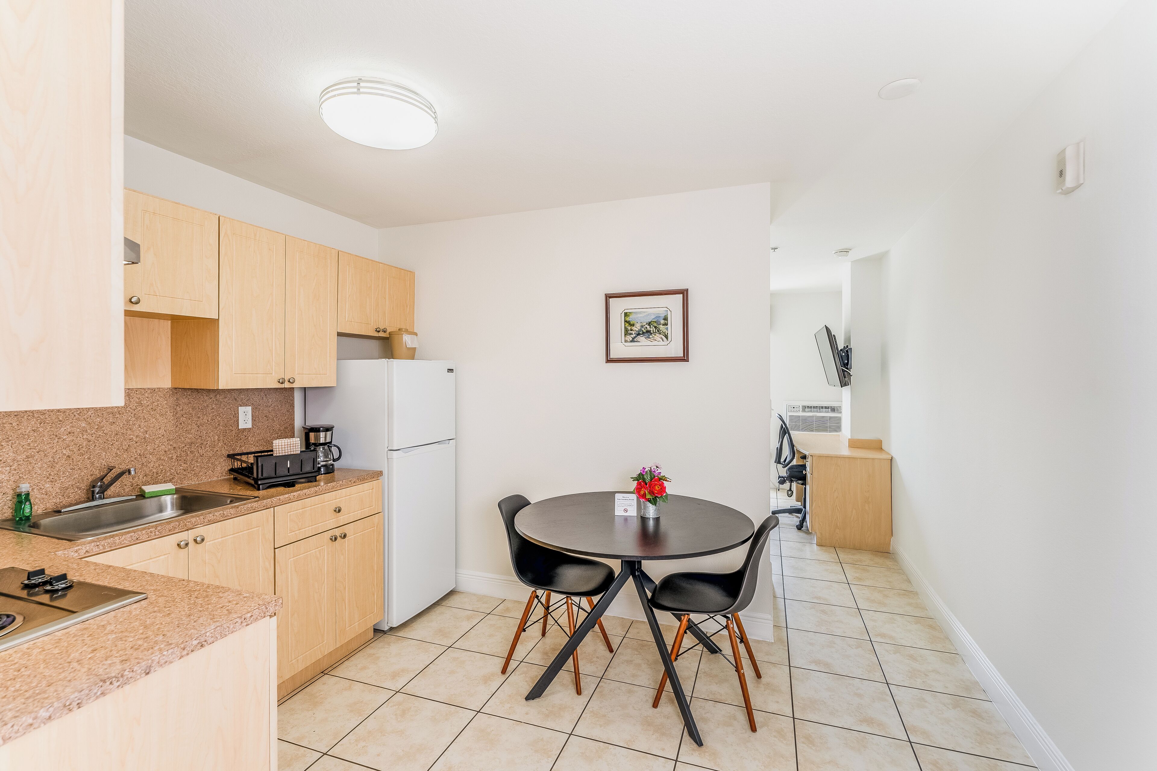 Una cocina moderna con armarios de madera, una mesa de comedor con sillas y un refrigerador.