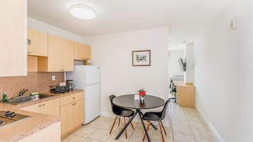 Una cocina moderna con armarios de madera, una mesa de comedor con sillas y un refrigerador.