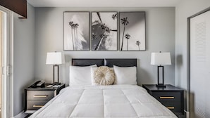A hotel room with a large bed, two bedside tables with lamps, a phone on one table, and a wall with three framed pictures. - South River Suites (Miami)