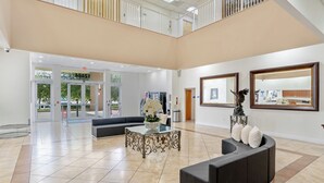 A spacious lobby with a modern design, featuring a seating area, a decorative table, and a large mirror. - South River Suites (Miami)