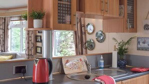 A modern kitchen with a kettle, a sink, and decorative plates on the wall. - A perfect countryside escape for lovers of the outdoors. (Ayr)