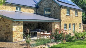 A stone house with a covered patio, solar panels, and a garden.