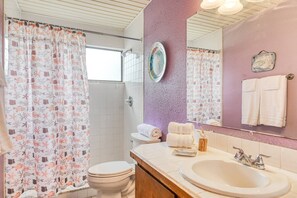 Ein Badezimmer mit Toilette, Waschbecken und einer Duschtasse mit Meeresmotiven.