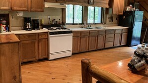 A kitchen with wooden cabinets, a stove, a refrigerator, and a sink.