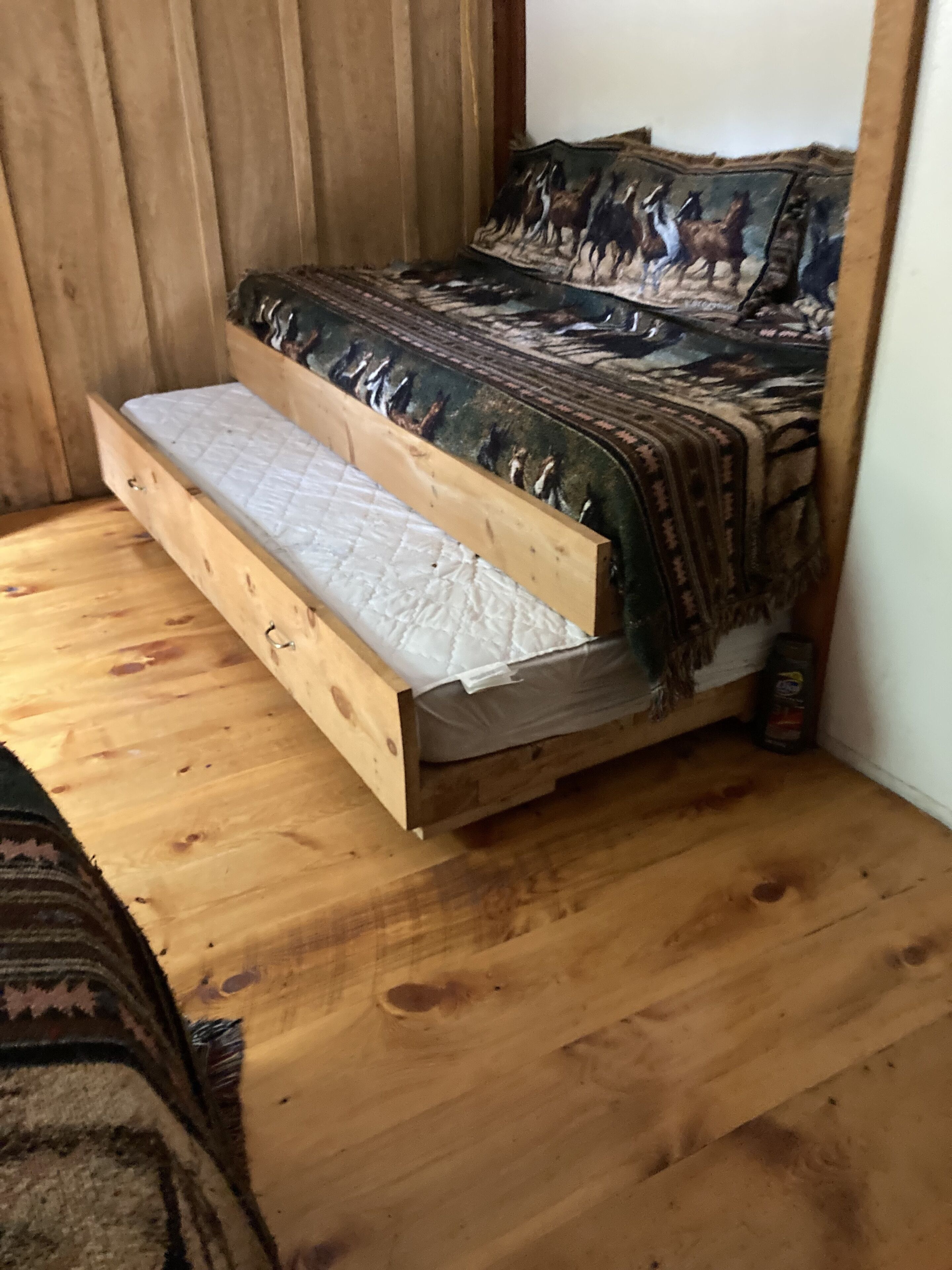 Ein Bett aus Holz mit gesteppter Matratze und einem gemusterten Bettbezug.