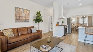 Un salon moderne avec un canapé en cuir marron, une table basse et un tableau accroché au mur.