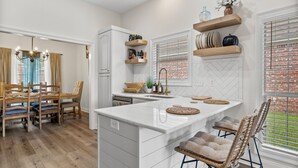 Une cuisine moderne dotée d’un îlot central, de chaises en bois et d’un coin repas avec une table et des chaises.